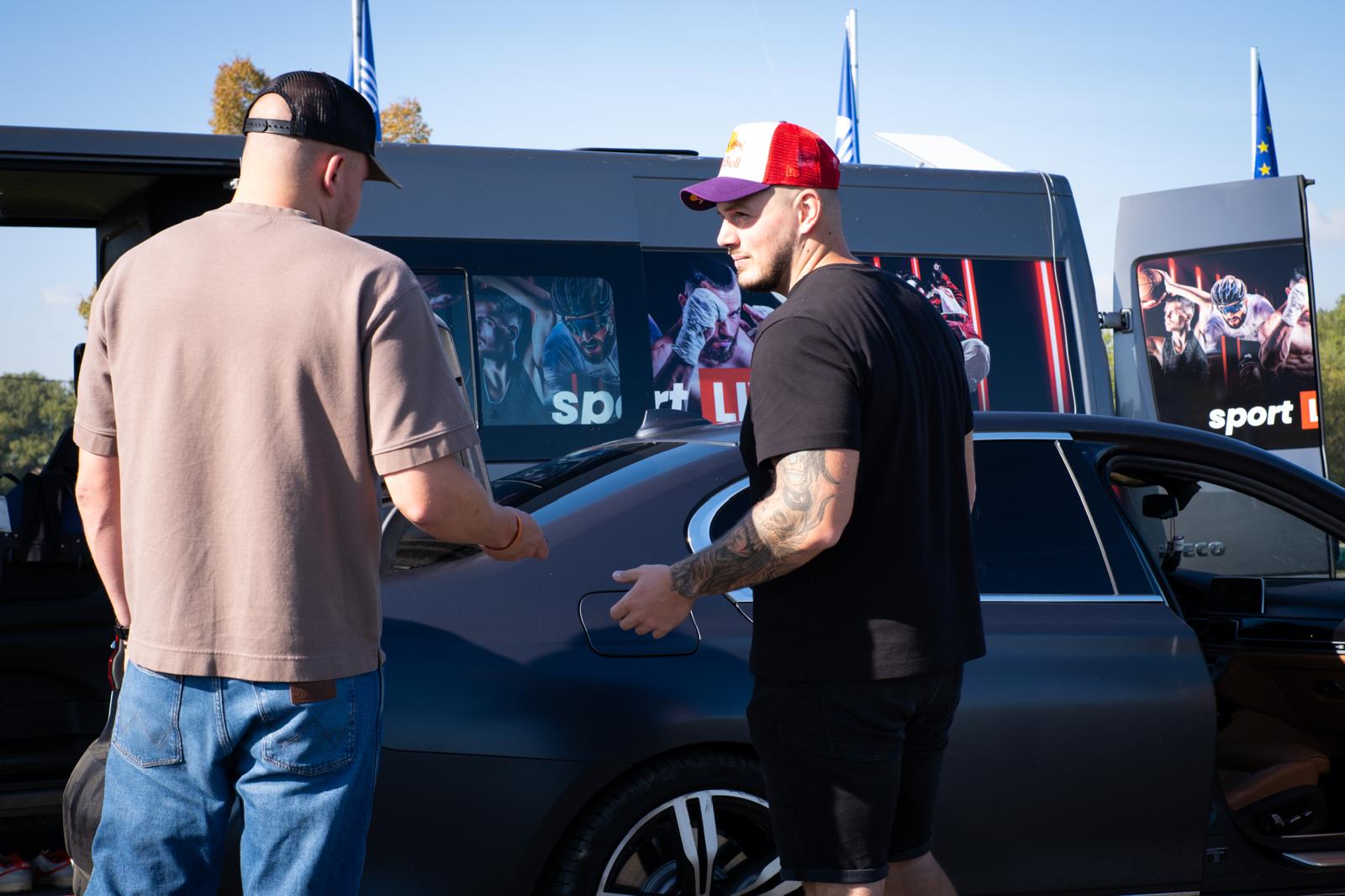 Jiří Hendrych a člen sportlive24.tv připravují přenosový vůz s polepem sportovních scén pro živé vysílání.